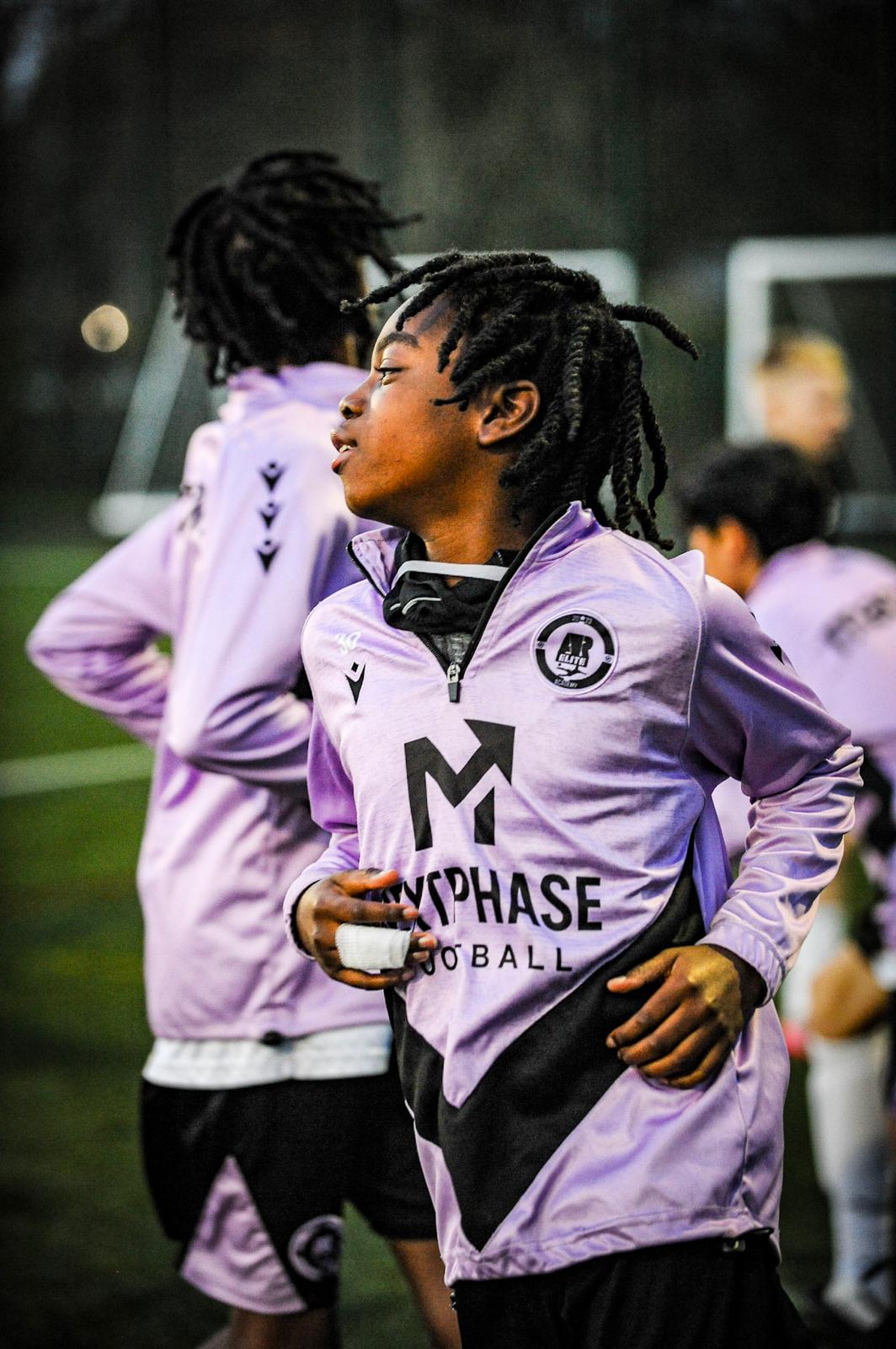 Next Phase Football players warming up together during an evening training session.