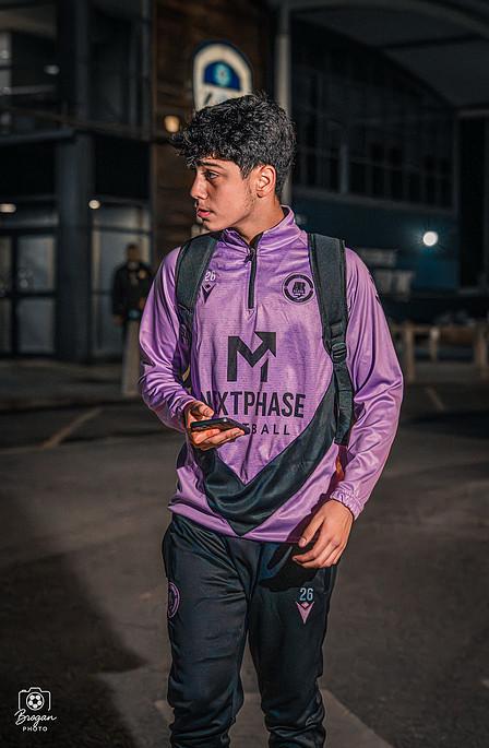 Portrait of a Next Phase Football player in branded training kit outside a professional stadium.