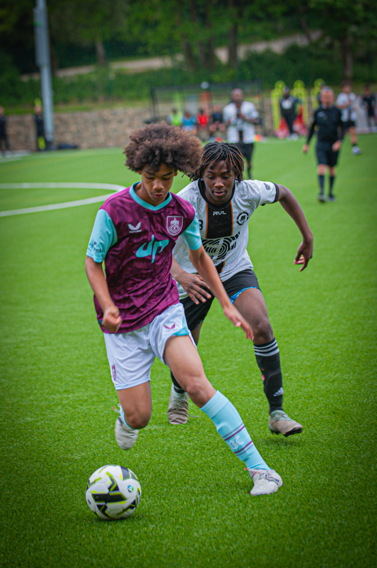 Two young players competing for possession on a 4G pitch during a Talent ID fixture.