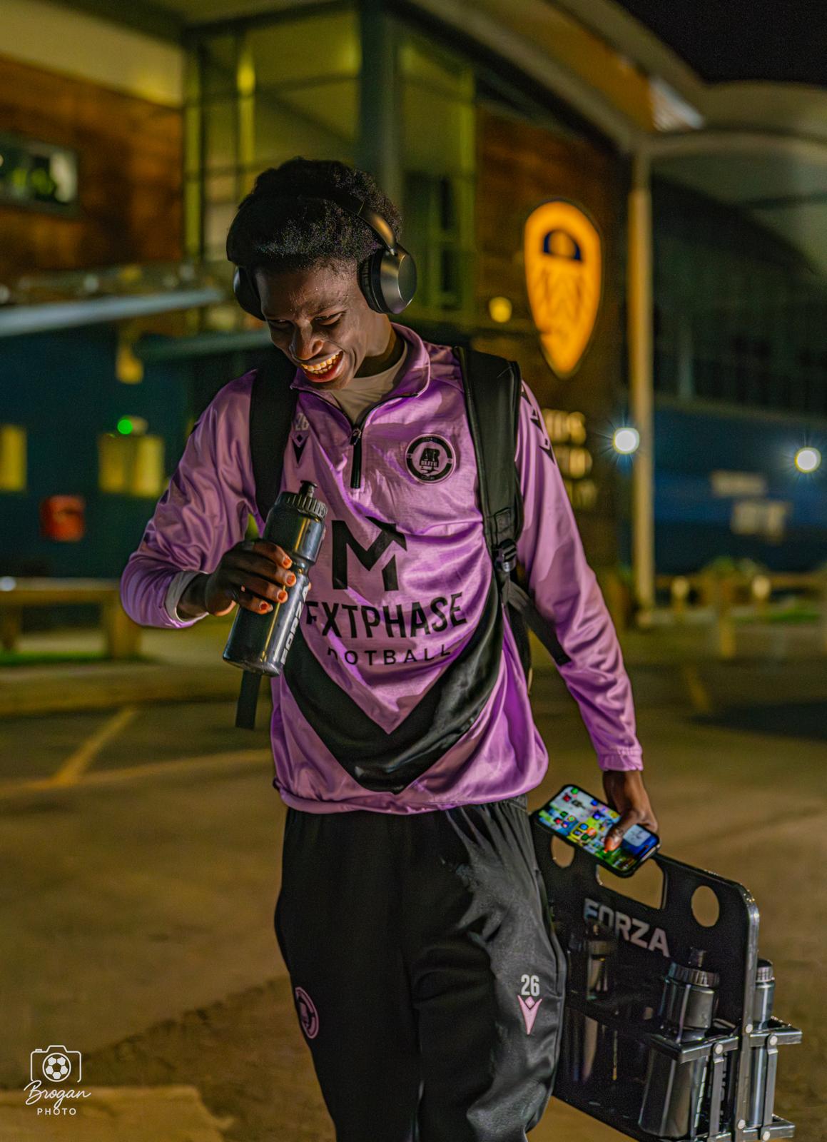 A Next Phase Football player arriving at a stadium at night carrying team water bottles.